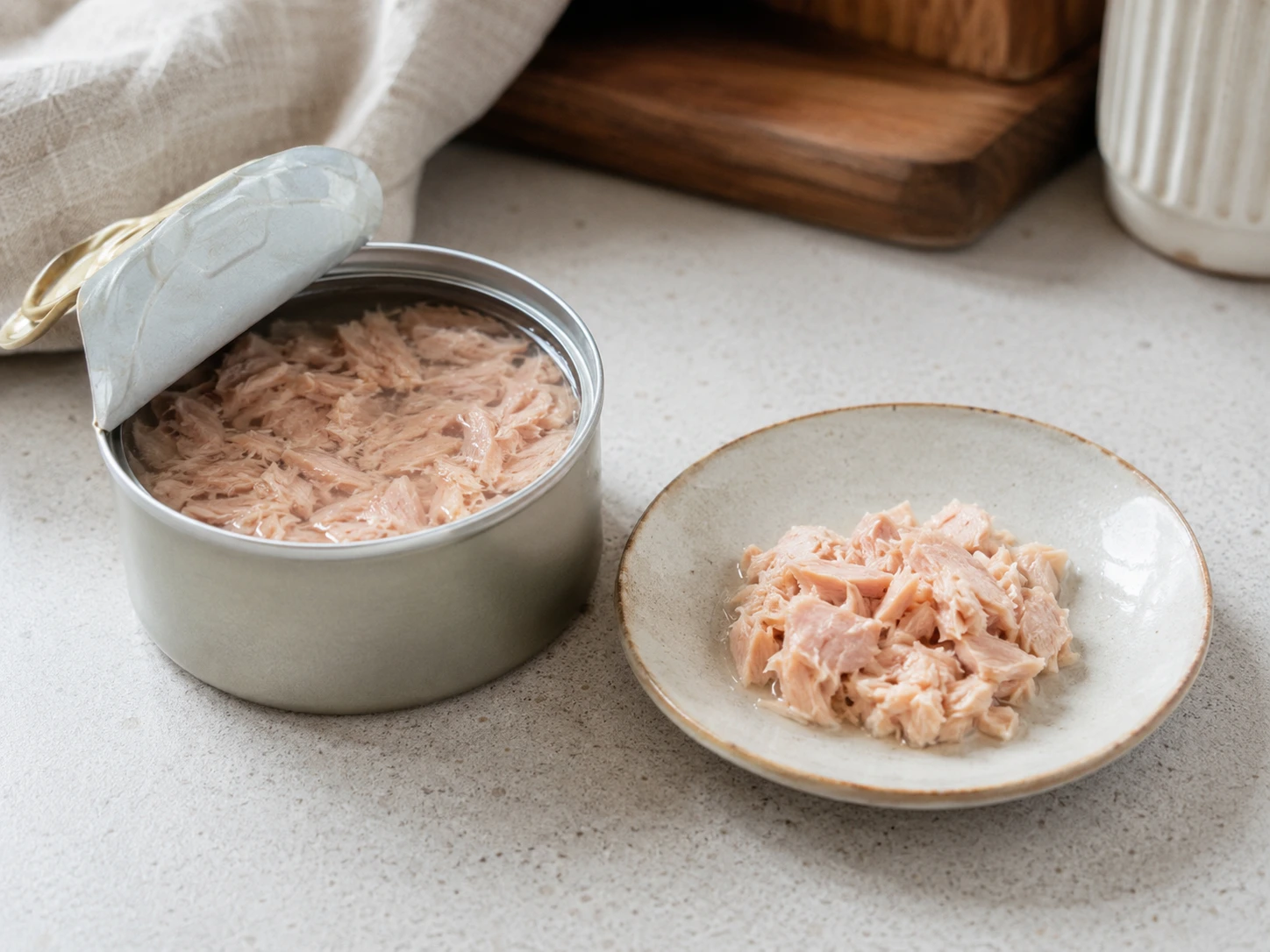 Plain canned tuna in water beside a small serving prepared for a cat